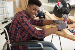 An image of a man on a wheelchair doing some work independently